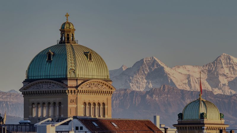 Foto: Das Bundeshaus in Bern im Abendlicht, dahinter Eiger und Mönch — Symbolbild aus dem Bildpool der Rubrik, nicht vom Ereignis selbst.